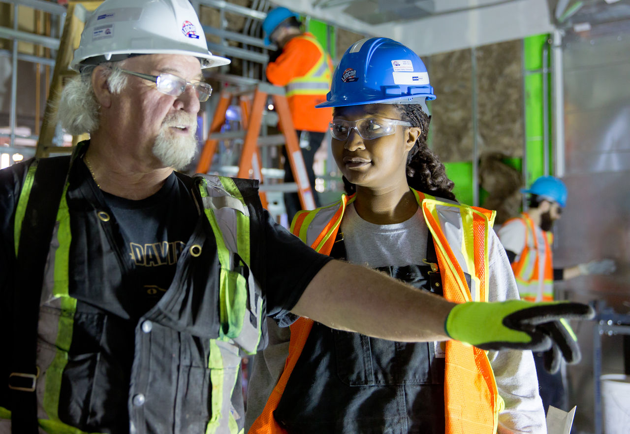 Construction worker mentoring younger construction worker