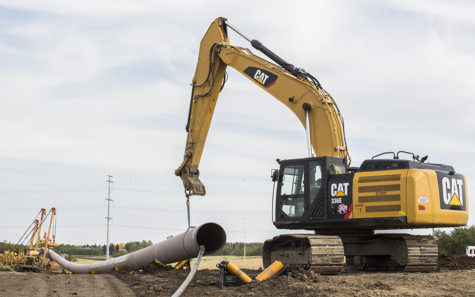 Excavator holding and moving pipe to install